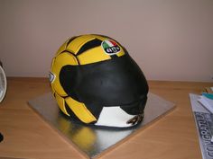 a helmet shaped cake sitting on top of a wooden table next to an alarm clock