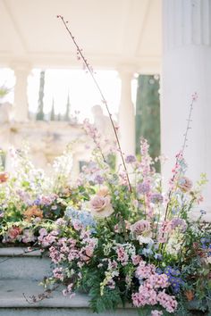 a bunch of flowers that are sitting in some kind of planter on the steps