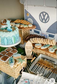 a table topped with cakes and cookies next to a vw bus