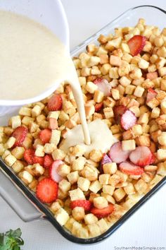 someone pouring dressing into a dish filled with strawberries and cubed breadcrumbs