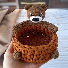 a small crocheted teddy bear sitting inside of a basket on top of a table