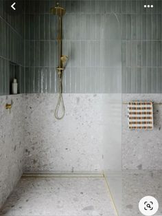 a bathroom with marble walls and floor, shower head and hand held faucet