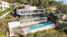 an aerial view of a house with a pool in the foreground and trees surrounding it