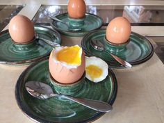 four plates with eggs and spoons sitting on top of each other in front of a glass table