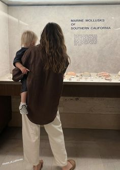 a woman holding a child in front of a museum display