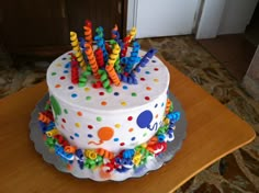 a birthday cake decorated with multicolored icing and sprinkles on a table