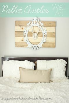 a bed with white sheets and pillows in front of a wall mounted deer antler