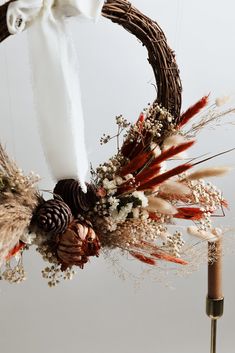 a wreath with feathers and pine cones hanging from it