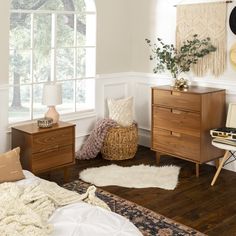 a bedroom with white walls and wooden furniture, including a bed, dresser, chair, rug and window