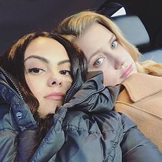 two women sitting in the back seat of a car, one is wearing a blue coat