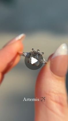 a person holding a diamond ring in their hand with the words artemus on it