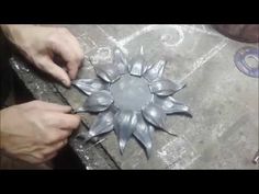 someone is working on something that looks like a sunflower ornament in silver