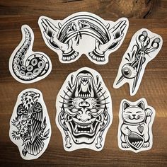 six stickers with different designs on wooden table next to scissors and an eyeball