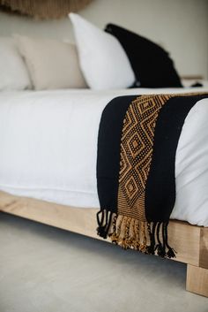 a bed with white sheets and pillows on it's headboard is made out of wood