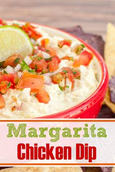 a red bowl filled with chicken dip surrounded by tortilla chips and lime wedges