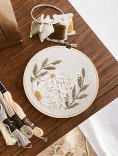 a wooden table topped with embroidery and thread