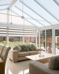 a living room filled with furniture and lots of windows covered in white coverings next to a brick building