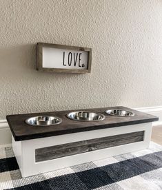 a dog bowl stand with three bowls on it and a love sign above the top