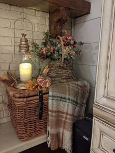 a basket filled with flowers sitting on top of a shelf next to a candle and blanket