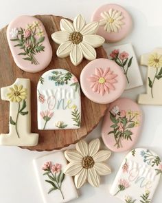 decorated cookies with flowers and the number one on them are sitting on a wooden platter