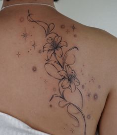 a woman's back with flowers and stars on her left shoulder, tattoo style