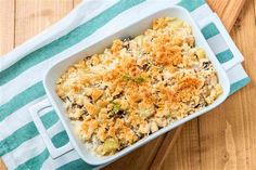 a casserole dish with chicken and vegetables in it on a blue and white towel