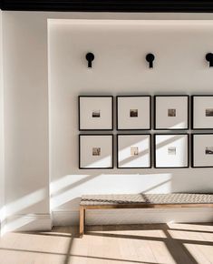 a white room with several framed pictures on the wall and a bench in front of it