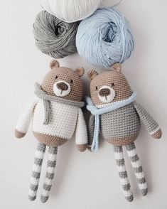 two crocheted teddy bears are next to balls of yarn on a white surface