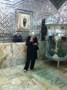 a man standing in front of a wall covered in mirrors and mosaic tiles, talking on a cell phone