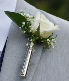 a boutonniere with a white rose and baby's breath