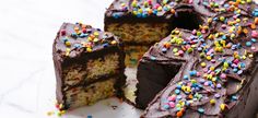 a cake with chocolate frosting and sprinkles is cut in half on a plate