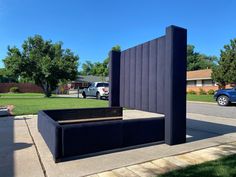 a bed sitting on the side of a sidewalk next to a green grass covered field