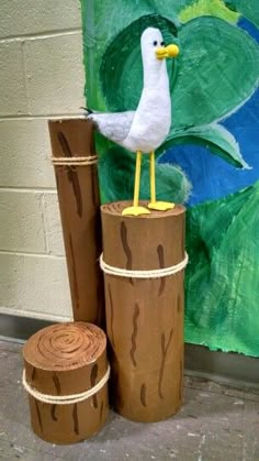 a seagull sitting on top of two logs in front of a painting