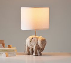 an elephant lamp sitting on top of a table next to books and a bookcase