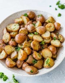 a white bowl filled with potatoes and parsley