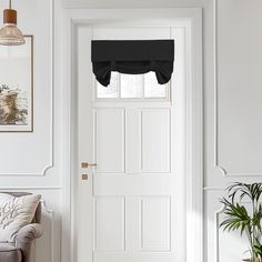 a living room with white walls and black drapes on the window sill over the door