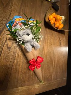 a bouquet of flowers with a teddy bear in it on a table next to oranges