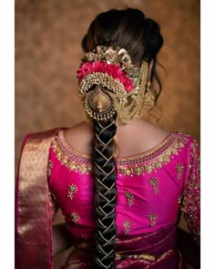 a woman wearing a pink and gold sari with braids in her hair, looking down