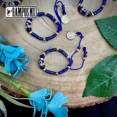 the blue bracelet is next to a flower on a wooden table with leaves and flowers