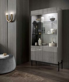 an elegant display cabinet in the corner of a room with grey walls and wooden floors