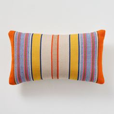 an orange and blue striped pillow sitting on top of a white wall