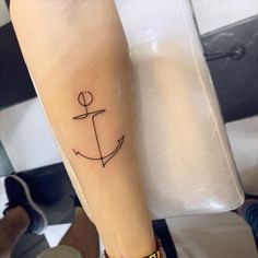 a small anchor tattoo on the arm