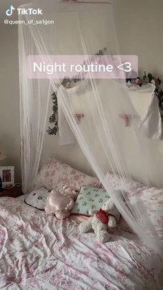 a bed with a white canopy over it and stuffed animals sitting on the pillows in front of it