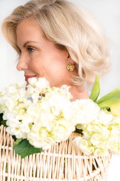 a woman holding a basket with white flowers in it and smiling at the camera,