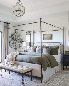 a bedroom with a canopy bed and pillows on the floor in front of a window