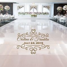 a wedding reception hall decorated with white and gold chairs, floral centerpieces on the dance floor