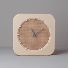 a beige clock sitting on top of a white table next to a gray wall and floor