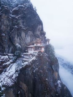 a mountain side with a building on top of it in the middle of snow covered mountains