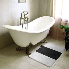 a bath tub sitting next to a window in a bathroom with a rug on the floor