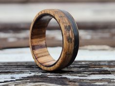 a wooden ring sitting on top of a piece of wood with black inlays